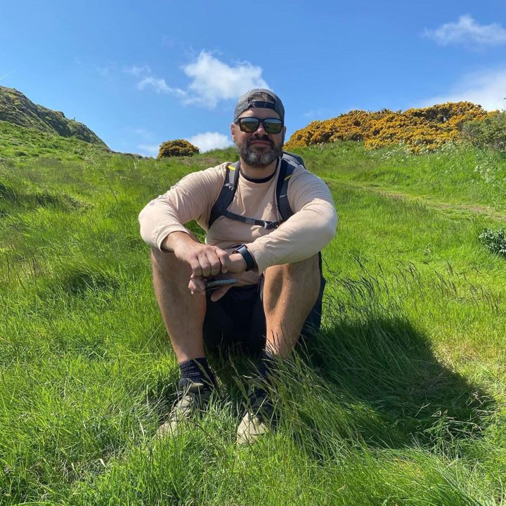 Will Stojcic, founder of Ever Wunder, sitting on a grassy hillside in Scotland
